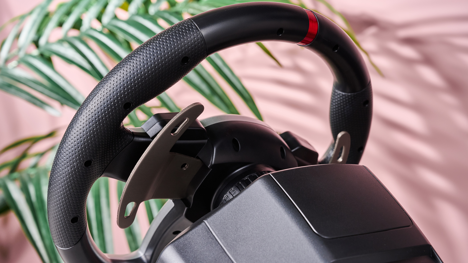 Rear of Hori Force Feedback Racing Wheel DLX on desk with plant and pink wall in background