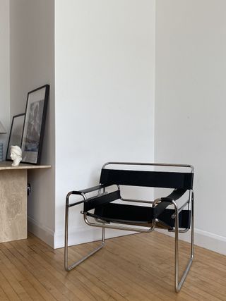 A chair with tubular steel frame and black leather seat and armrests in a room with white walls and wooden floor