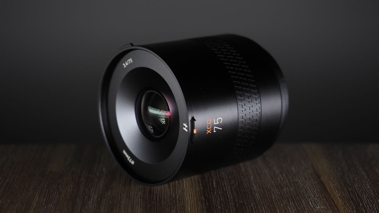 Hasselblad XCD 75P lens, on a wooden surface, against a dark background