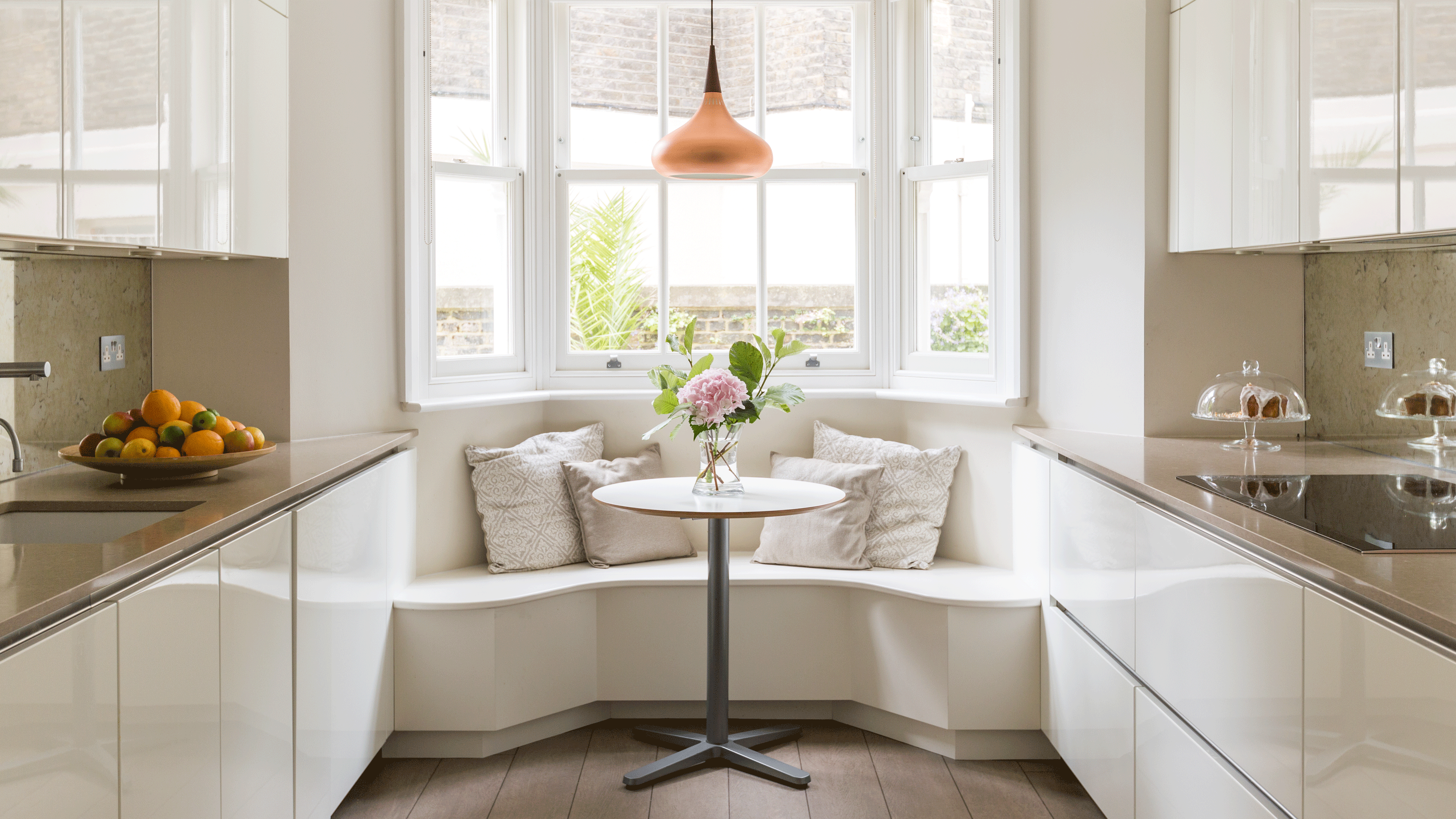 Dining nook with window seat using white seating and white dining table