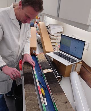 A photo of a scientist working with a long core sample in the lab
