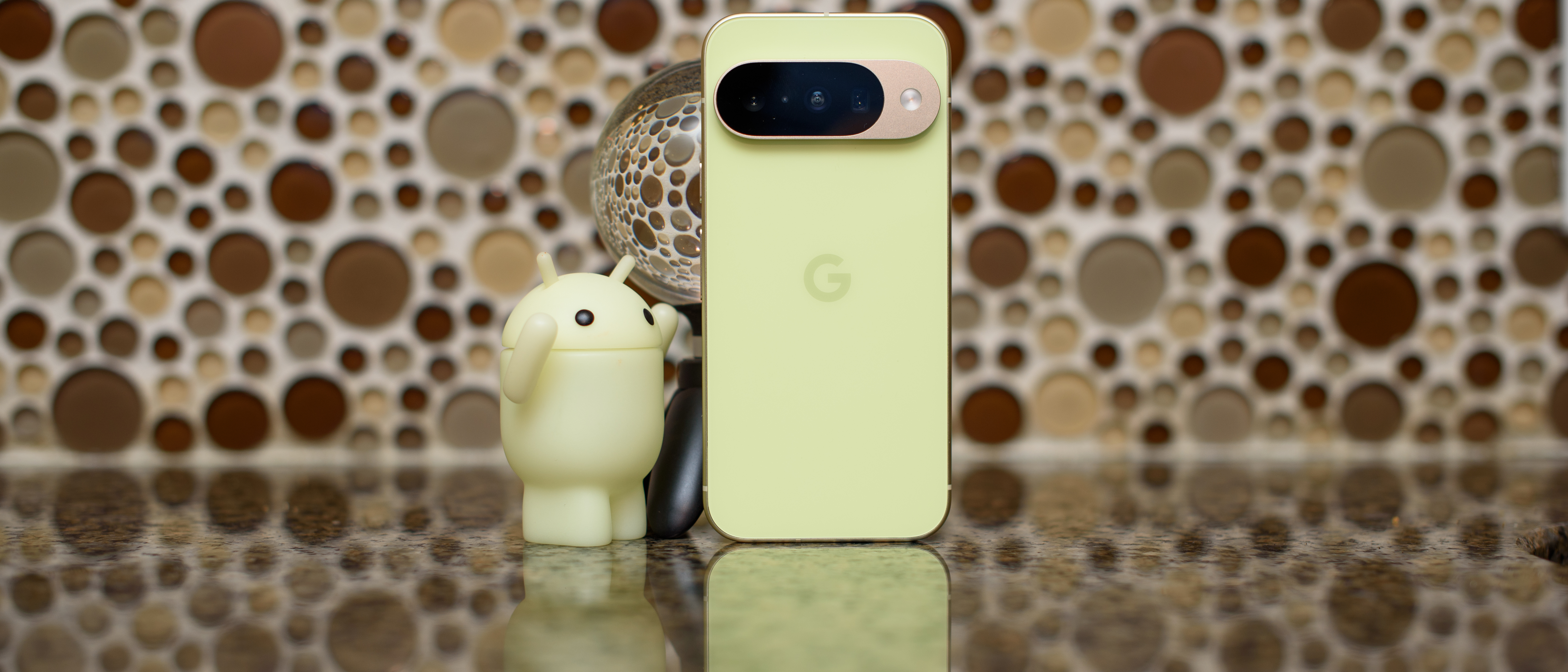 Google Pixel 10 in Lemongrass against a bubbly backsplash