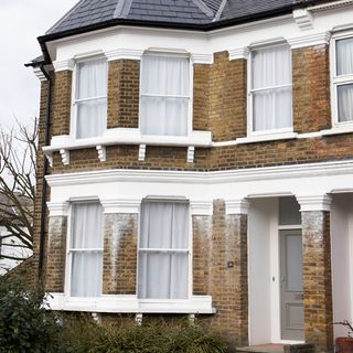 house exterior with white window and bricked wall