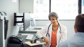 Patient speaks to smiling female doctor in a clinic.