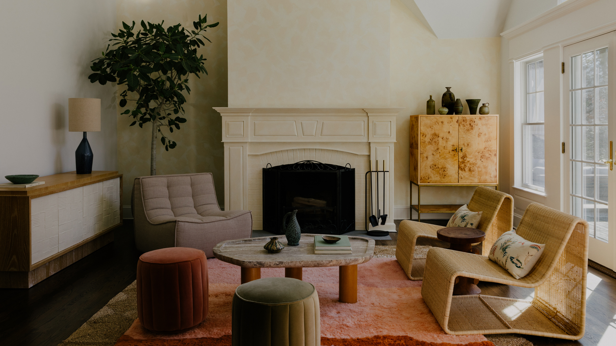 large living room with pink rug, round coffee table and two round footstools
