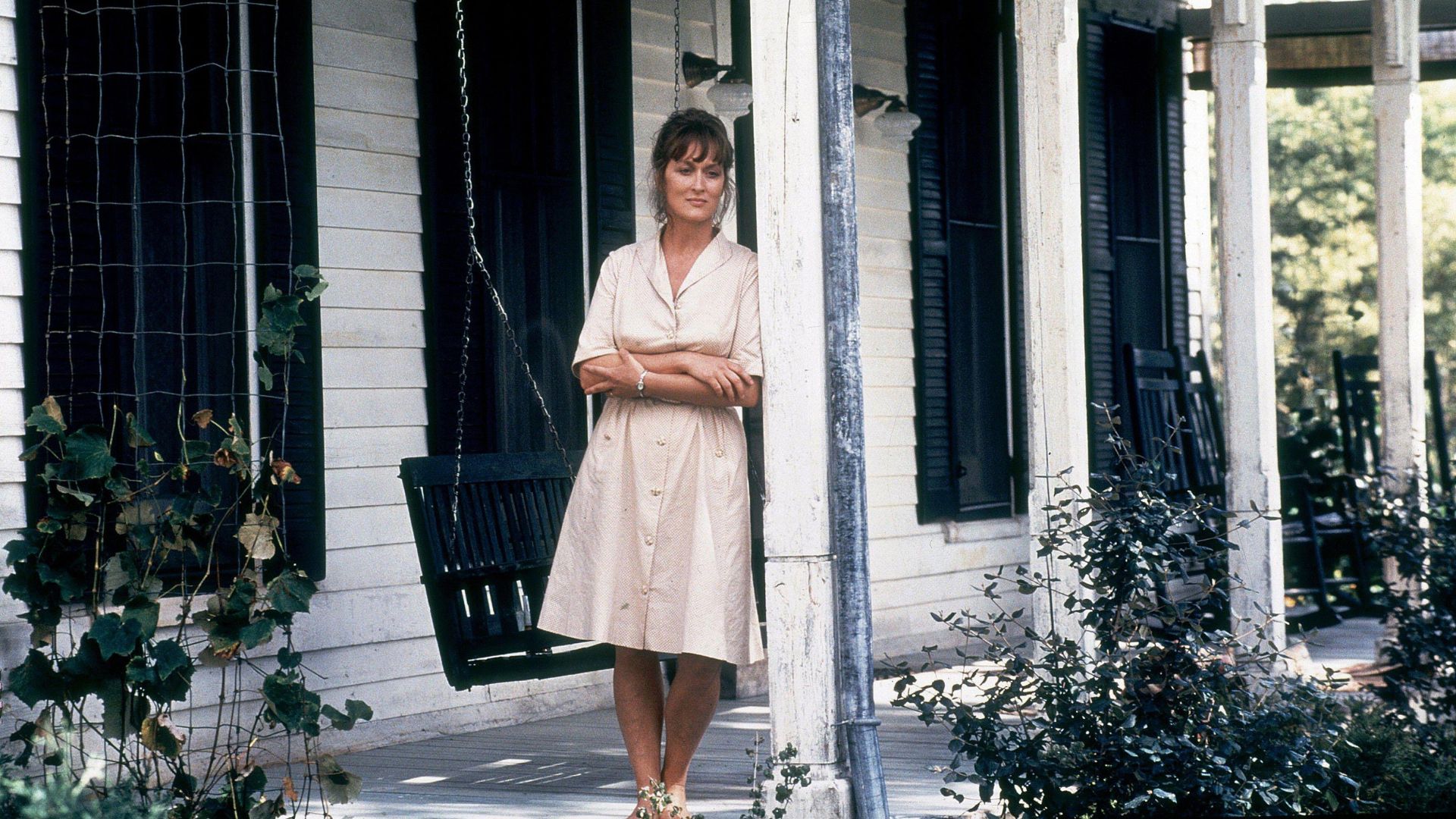 Meryl Streep leans against a porch post in the movie Bridges of Madison County