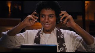 Jaafar Jackson smiling as he puts some over-ear headphones on to record a song in Lionsgate's Michael Jackson movie
