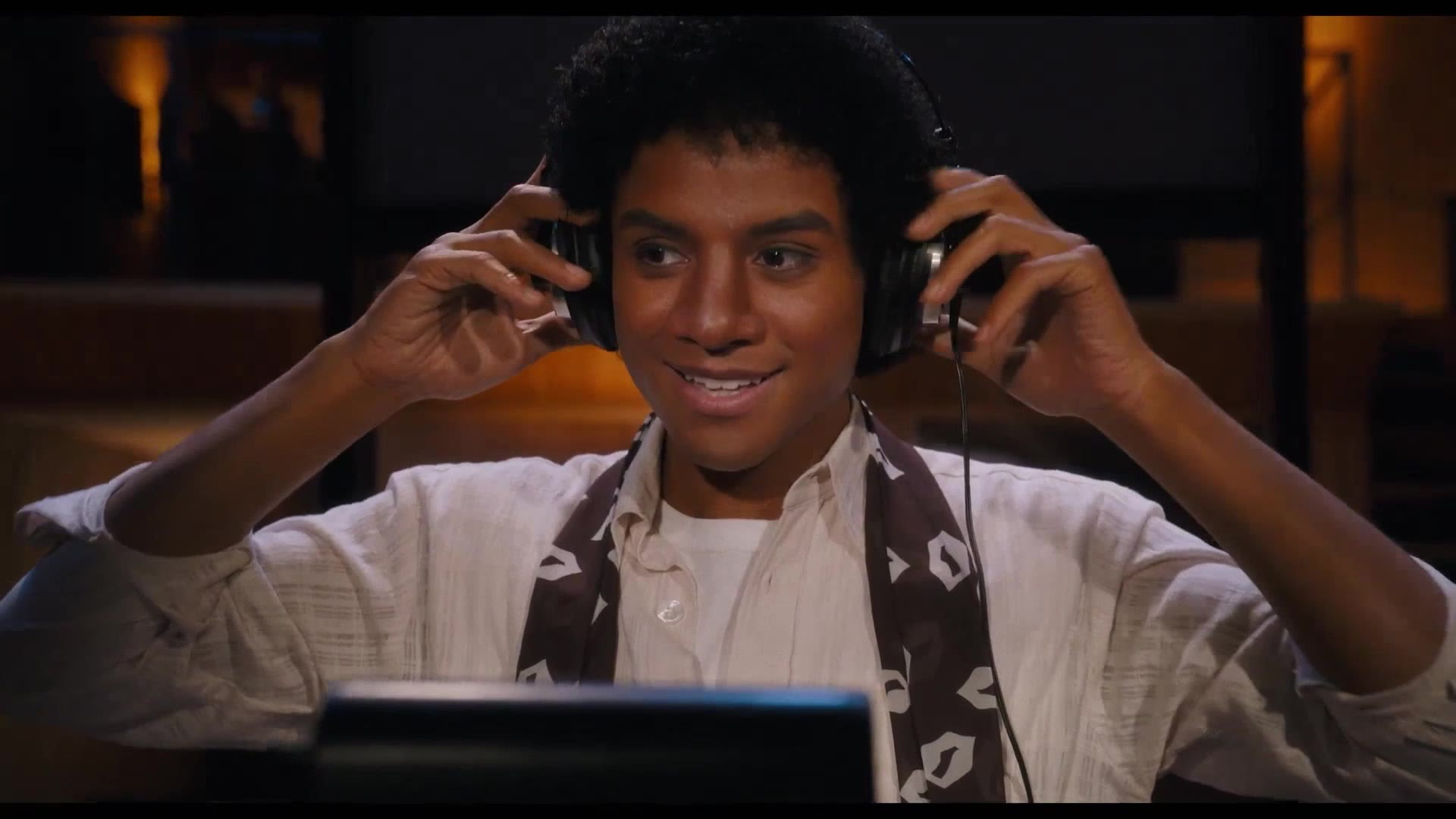 Jaafar Jackson smiling as he puts some over-ear headphones on to record a song in Lionsgate's Michael Jackson movie