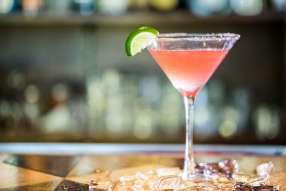 Pink Cosmopolitan cocktail in a martini glass with lime garnish