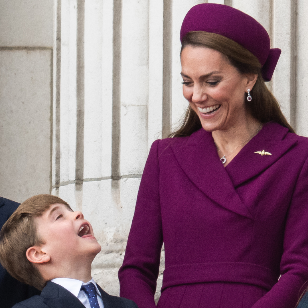 Princess Kate in a berry coat and hat, laughing looking at Prince Louis