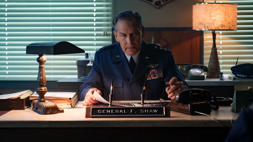 James Remar as General Shaw, sitting at his desk in uniform and smoking a cigar