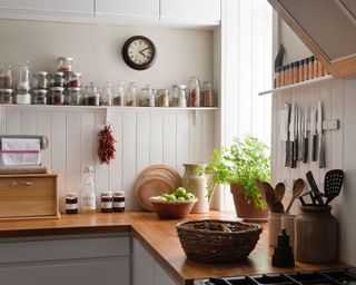 A country kitchen with open shelving, food containers and wood work top