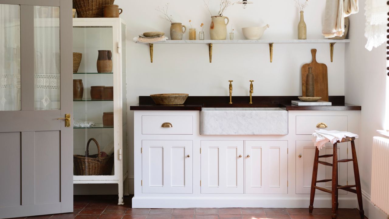 white pantry with white walls and cabinetry, black countertop, open shelving, artisan ceramics and wooden boards, wood stool, free standing glazed unit, deVOL