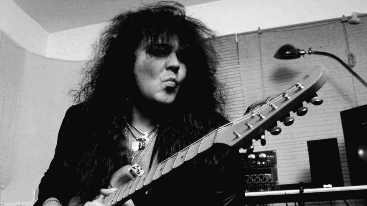 Ynwgie Malmsteen playing guitar in a dressing room in 1997