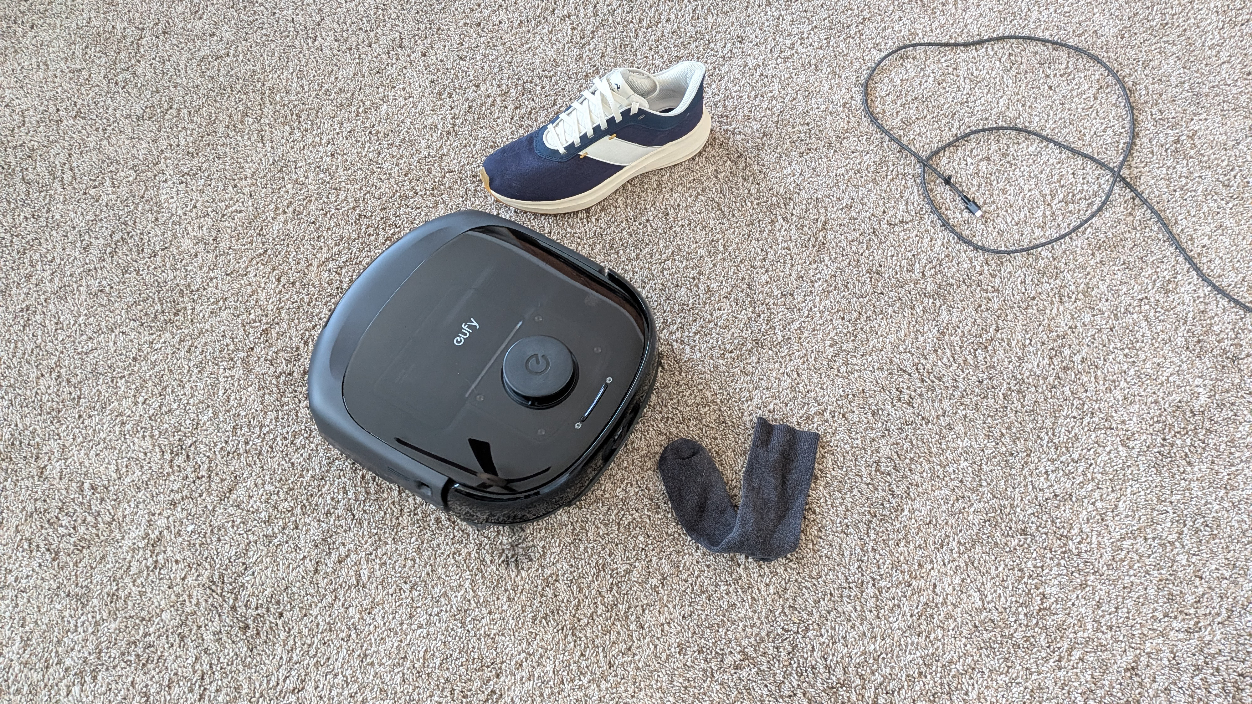 Eufy E25 Omni surrounded by obstacles on a carpeted floor