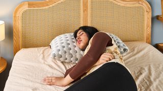 Woman sleeping on her side on the Layla Kapok Pillow in a brightly lit room