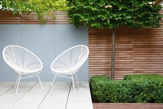 modern chairs on paving in garden designed by Lucy Wilcox Garden Design