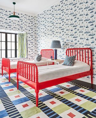 Navy blue boat print wallpaper in kids double bedroom with red painted bed frames and fun decor, crittal windows