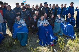Expedition 35 Commander Chris Hadfield of the Canadian Space Agency (CSA), left, Russian Flight Engineer Roman Romanenko of the Russian Federal Space Agency (Roscosmos), center, and NASA Flight Engineer Tom Marshburn sit in chairs outside the Soyuz Capsule just minutes after they landed in a remote area outside the town of Dzhezkazgan, Kazakhstan, on Tuesday, May 14, 2013.