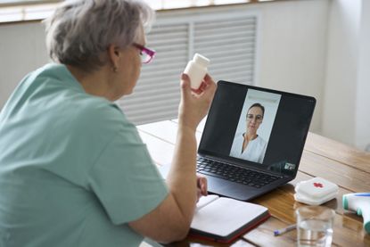 Senior woman taking assistance from doctor through video call at home - stock photo