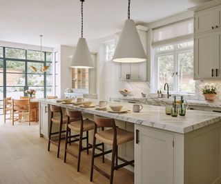 A neutral open plan kitchen diner with an island and round dining table