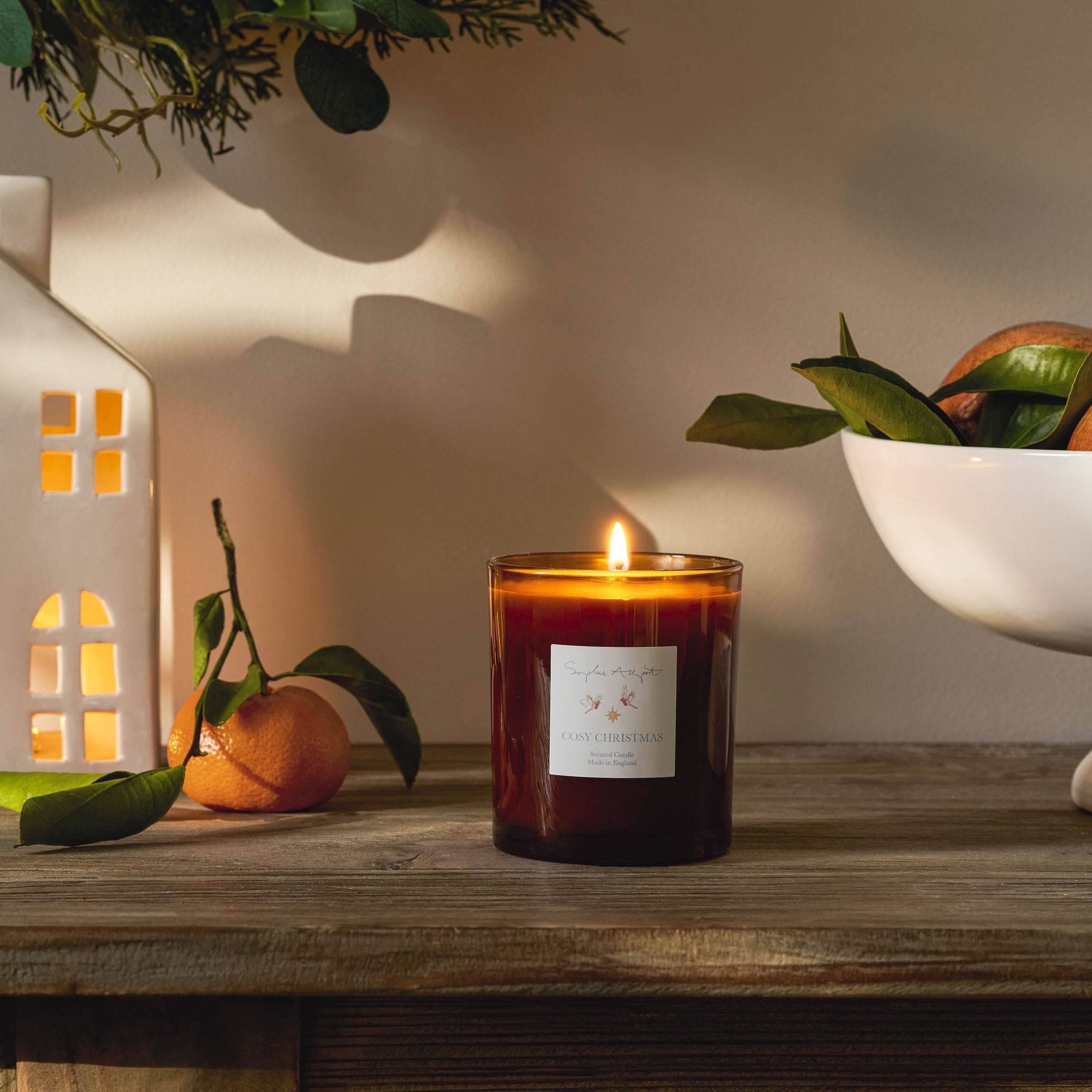 Candle in amber container burning on a wooden table