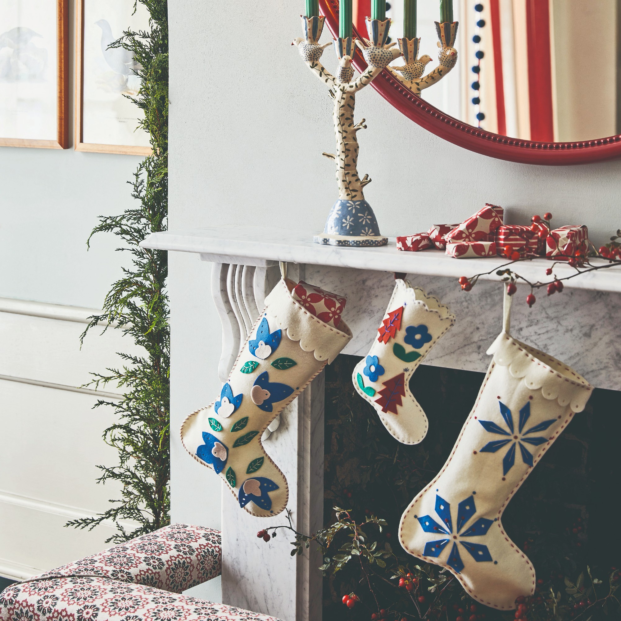 A fireplace decorated for Christmas with felt folk-style Christmas stockings