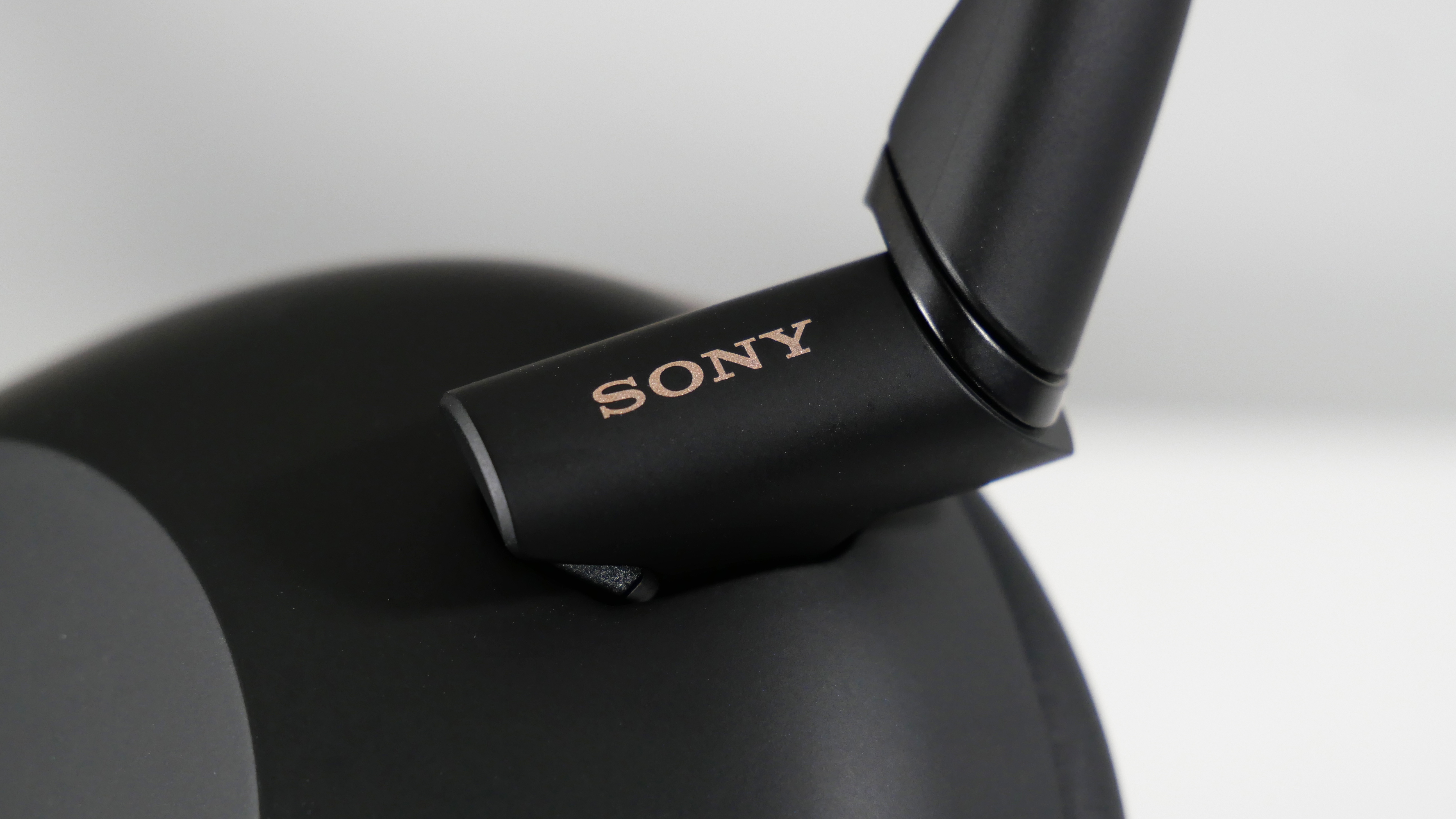 Sony WH-1000XM6 standing up on a white desk at an angle, highlighting the Sony logo.