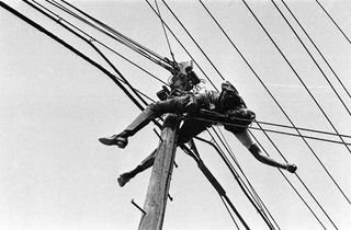 Black and white photograph of man electrocuted on a post