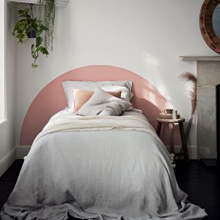 bedroom with white wall peach semi circle headboard and black flooring