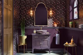 A bathroom with purple wallpaper and purple painted woodwork including a vanity and a dado rail