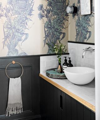 A small bathroom with built in storage and patterned wallpaper