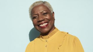 woman wearing yellow smiling on blue background