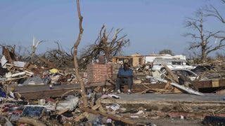 A man sits among the wreckage from a tornado that went through western Mississippi. 