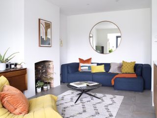 modern living room with white walls, a navy sofa, aztec rug and colourful cushions