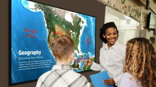 A smiling teacher showing a map of Germany to students on the new Sharp NEC Display.