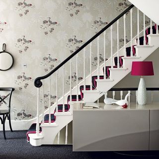 staircase with wallpaper on wall and lamp