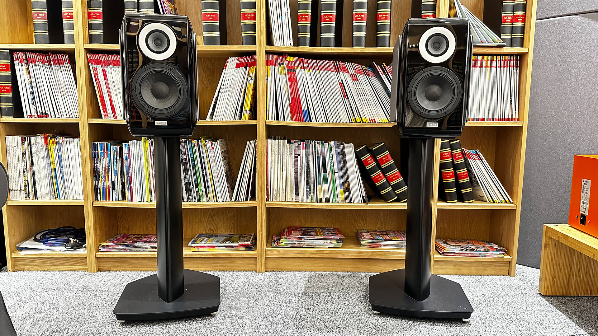 TAD ME1TX standmount speakers on stands in front of bookcase