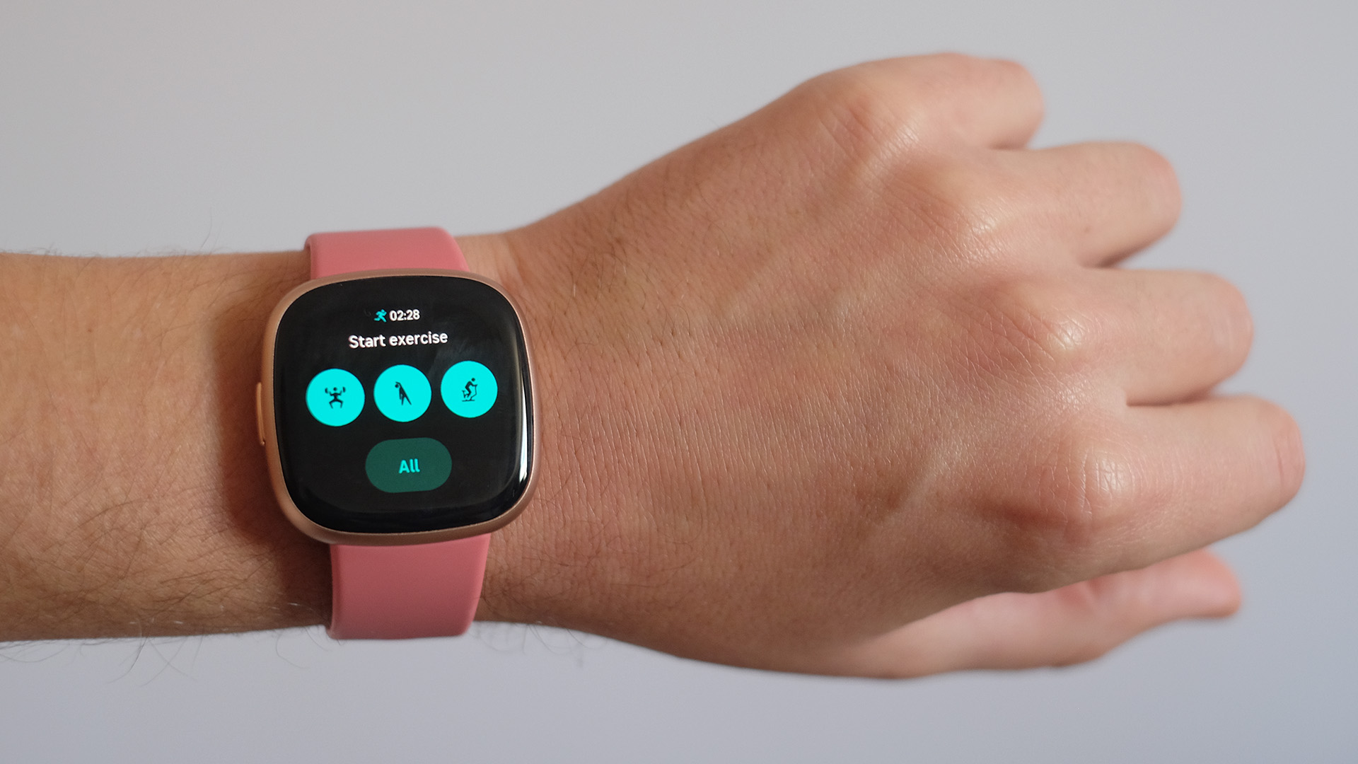 Fitbit Versa 4 being worn on a wrist with white background.