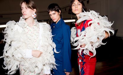 Models wear white feathered jacket, blue blazer and red dress with white feathered sleeves