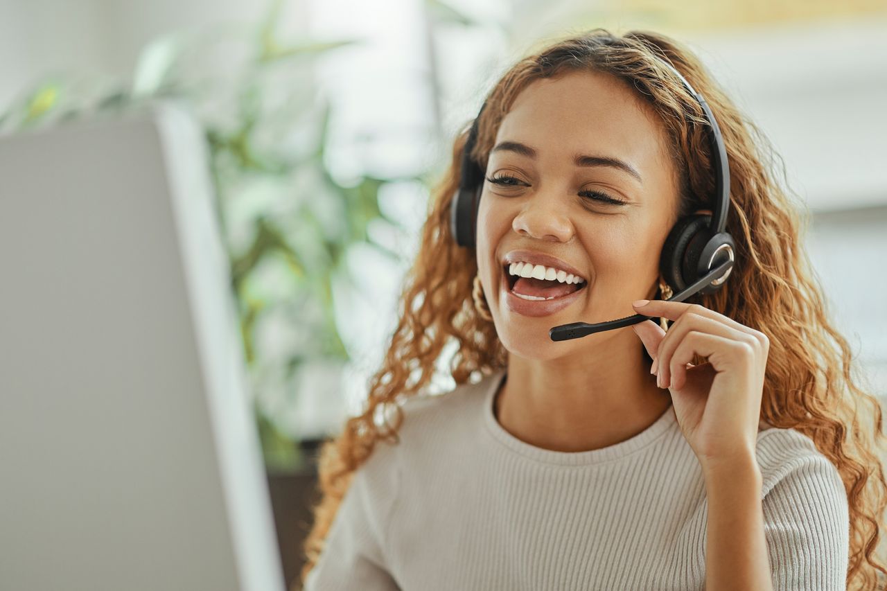 Customer service, happy and communication of woman at call center pc talking with joyful smile. Consultant, advice and help desk girl speaking with clients online with computer headset mic.