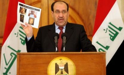 Iraqi PM Nouri al-Maliki holds photos of the man idenitifed as Abu Ayyub al-Masri.