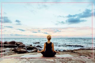 A woman meditating in front of the sea