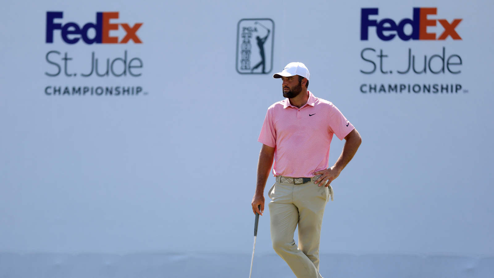 Scottie Scheffler waits on the green in front of a FedEx St. Jude Championship board