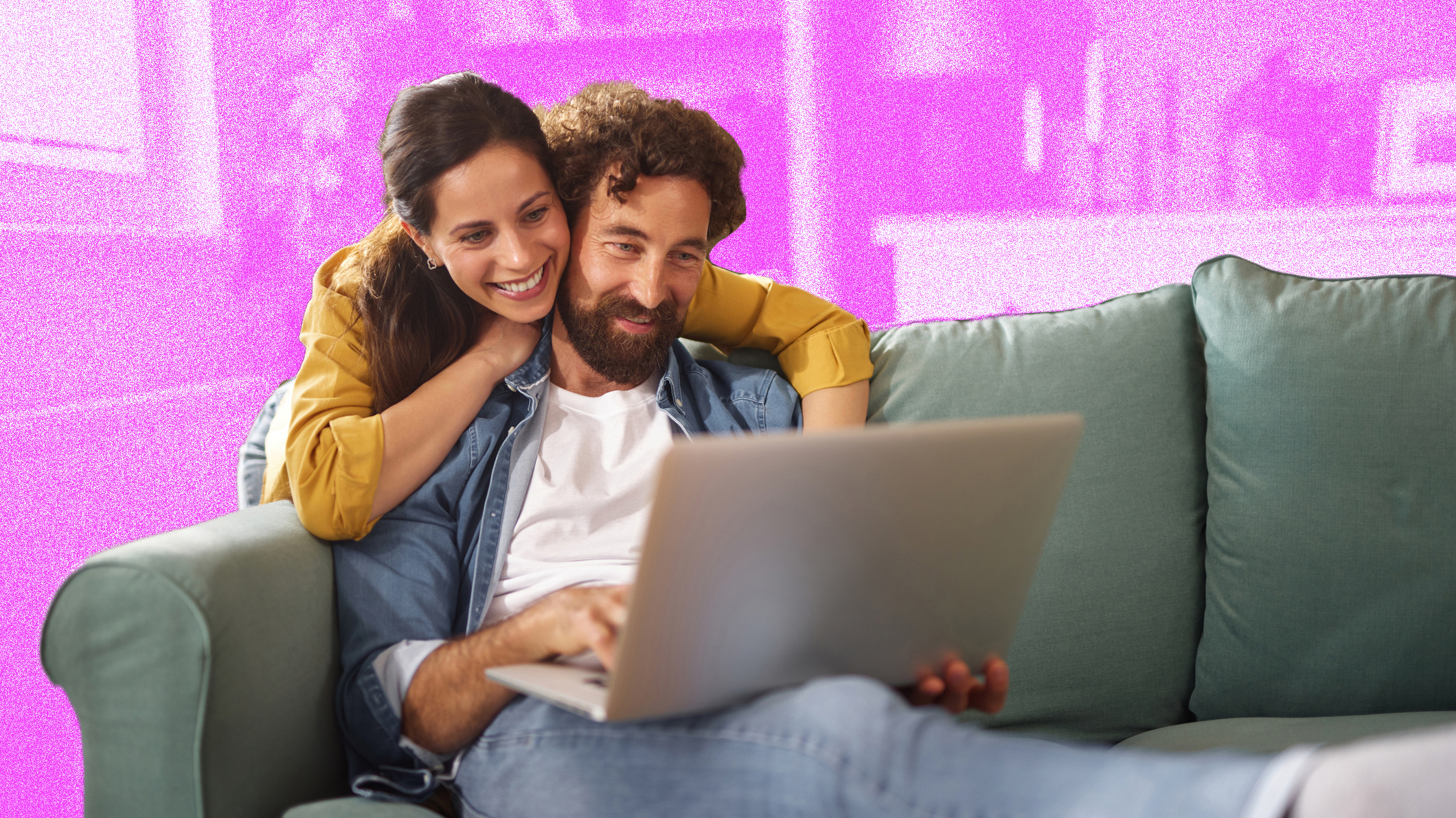 Young couple looking happy whilst looking at laptop on the sofa. 