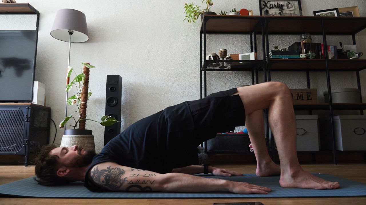 A man doing glute bridges in his living room