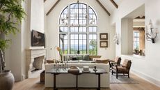 A neutral living room with a large window and vaulted ceilings