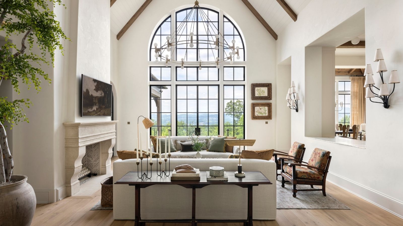 A neutral living room with a large window and vaulted ceilings