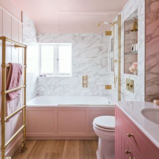 bathroom with pink panelling on bath, pink walls, marble tiles, and pink sink