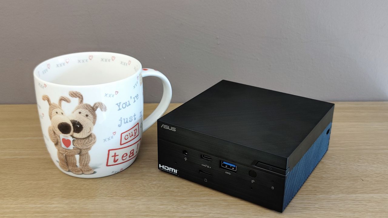 The Asus PN51 MiniPC on a desk next to a mug